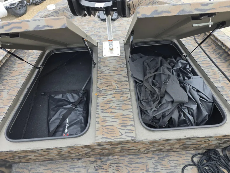 Slide: The Image of Open storage compartments on a 2025 Xpress H190B boat with camo pattern. - 8
