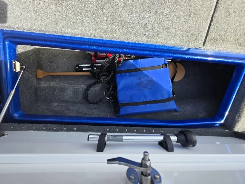 Slide: The Image of Storage compartment in a 2016 Phoenix 819 Pro boat with safety gear and paddle. - 29