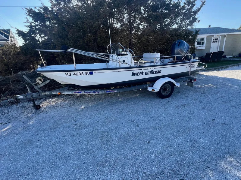 Slide: The Image of 2000 Boston Whaler 17 Montauk boat on trailer, labeled "Sweet emOcean," parked on gravel. - 1