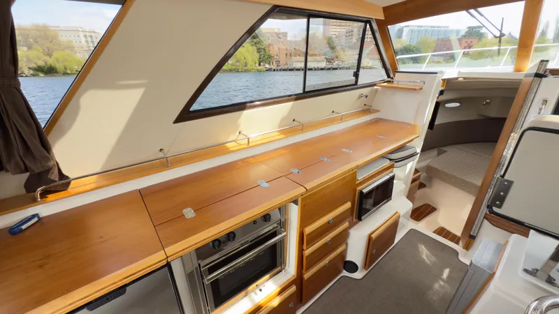 Slide: The Image of 2017 Cutwater C-302 Coupe interior with wooden cabinetry, modern appliances, and large windows overlooking water. - 3