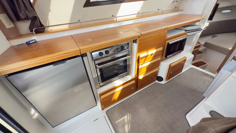 Slide: The Image of 2017 Cutwater C-302 Coupe interior kitchen with stainless appliances and wooden cabinetry. - 4