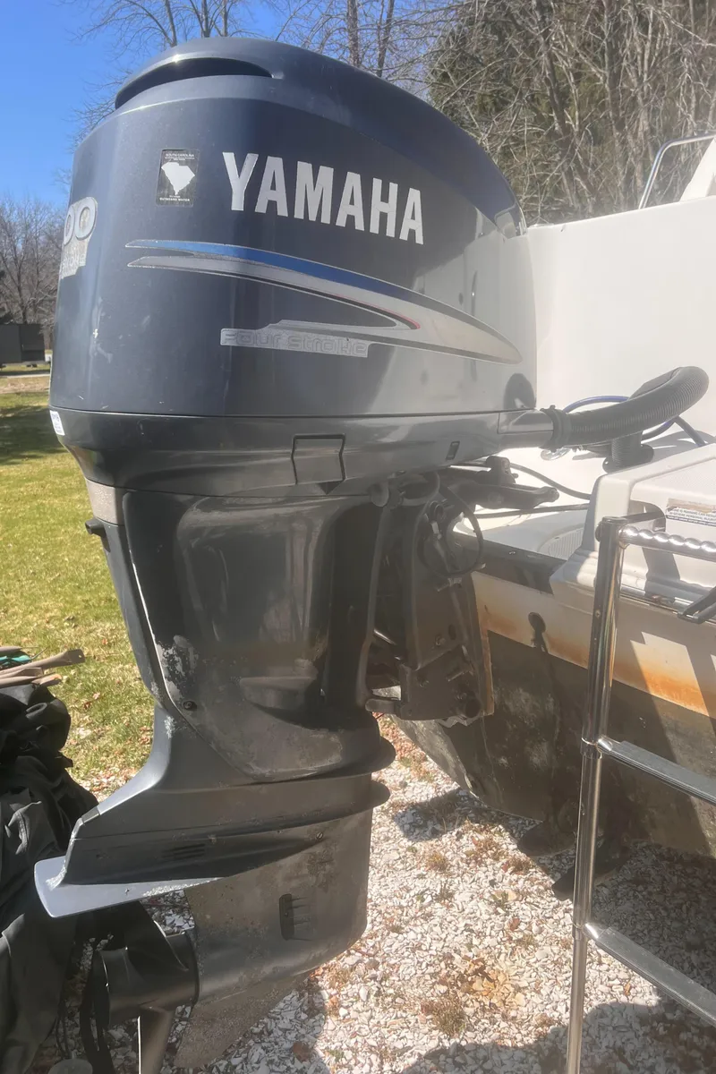 Slide: The Image of 2004 Robalo R225 Walkaround with Yamaha outboard motor, parked on gravel. - 14
