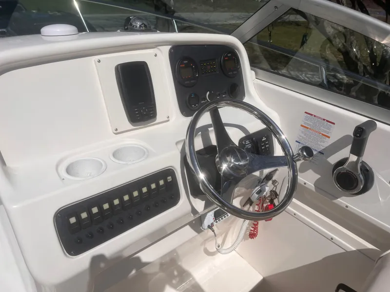 Slide: The Image of 2004 Robalo R225 Walkaround boat dashboard with steering wheel and control panel. - 18