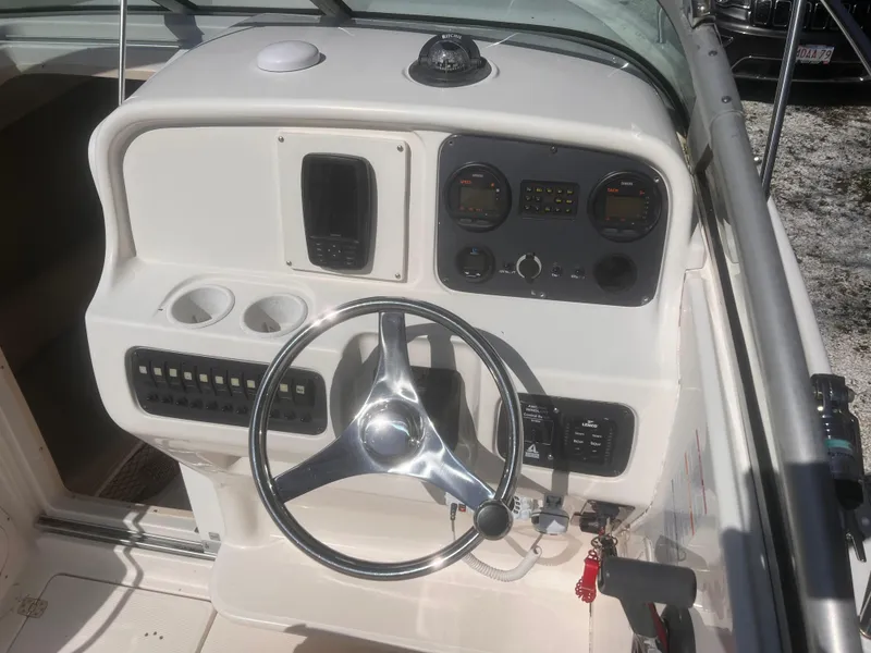 Slide: The Image of 2004 Robalo R225 Walkaround boat dashboard with steering wheel and control panel. - 19