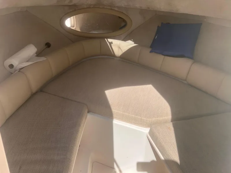 Slide: The Image of 2004 Robalo R225 Walkaround cabin interior with cushioned seating and oval window. - 21