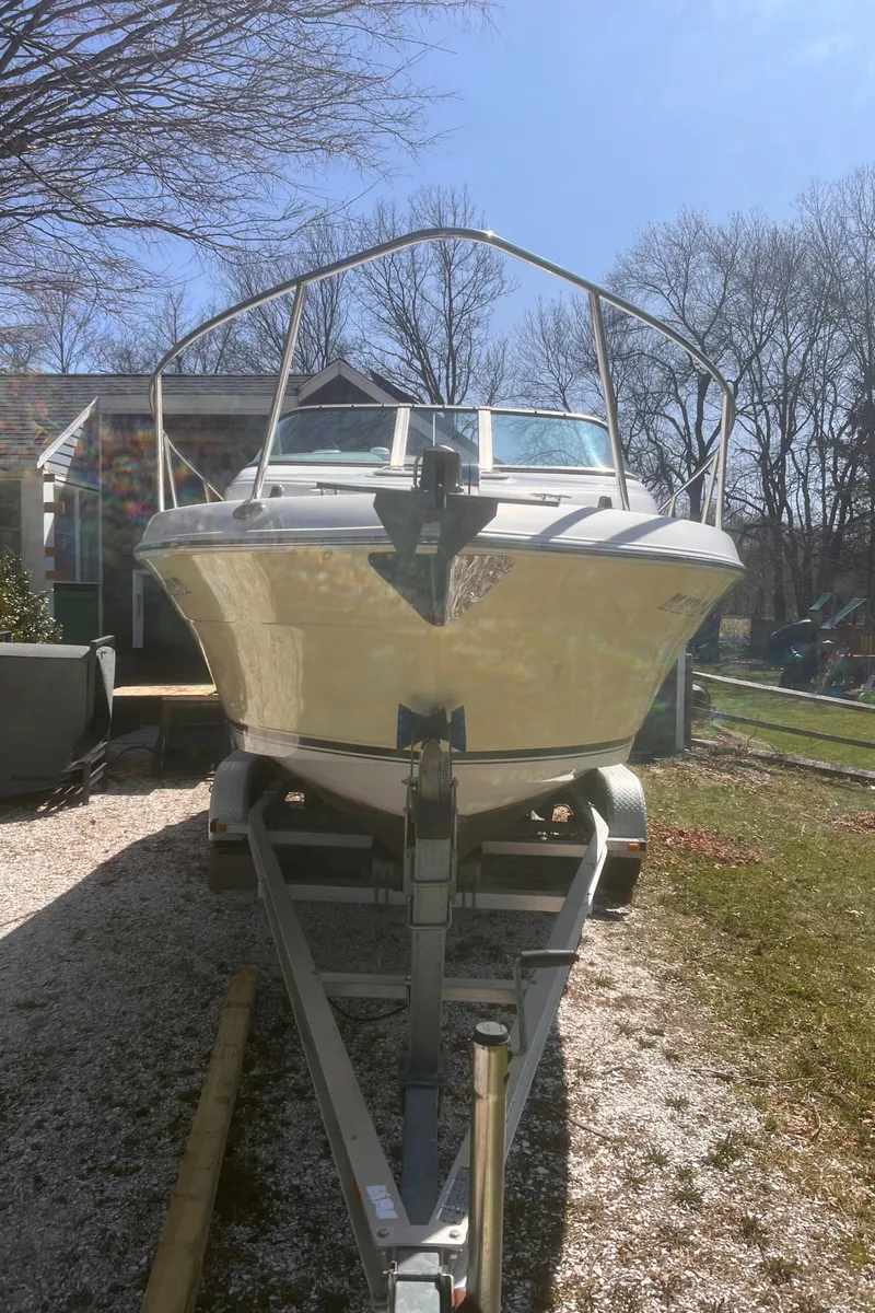 Slide: The Image of 2004 Robalo R225 Walkaround boat on trailer, parked outdoors under clear sky. - 42