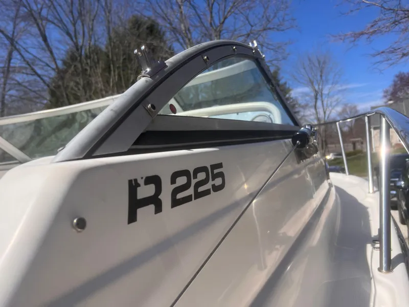 Slide: The Image of 2004 Robalo R225 Walkaround boat, close-up view, showcasing sleek design and windshield. - 6