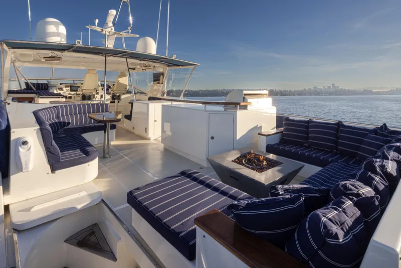 Slide: The Image of Luxurious 2003 Marlow 72C yacht deck with striped seating and fire pit, overlooking serene waters. - 24