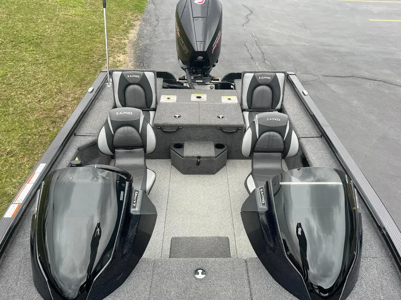Slide: The Image of 2019 Lund 1875 Pro-V Bass XS boat interior with seating and motor, parked on pavement. - 11