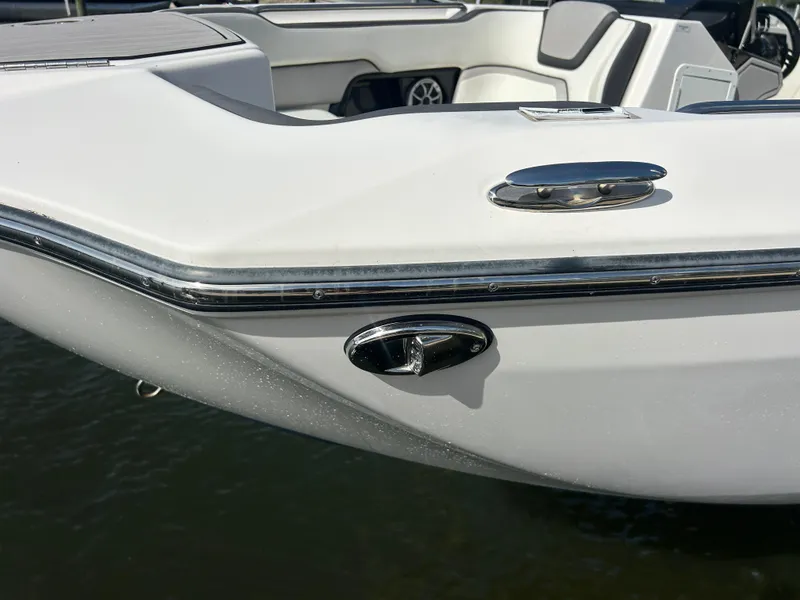 Slide: The Image of 2023 Yamaha Boats 252SD, sleek white exterior with chrome accents, docked on water. - 10