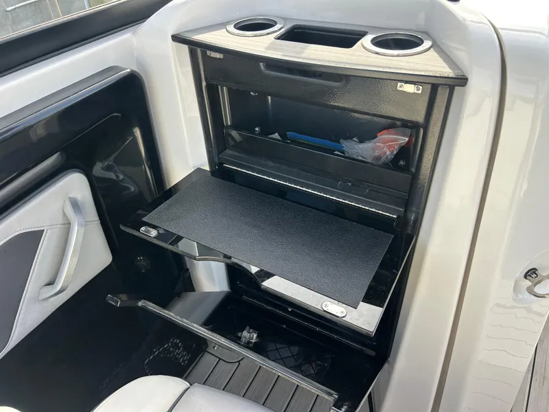 Slide: The Image of 2023 Yamaha Boats 252SD interior storage compartment with cup holders and shelves. - 23