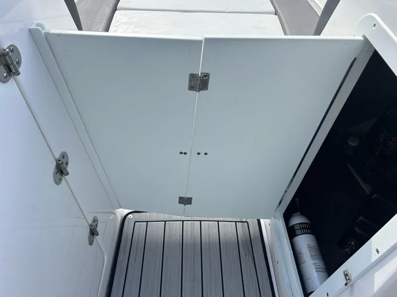Slide: The Image of 2023 Yamaha Boats 252SD interior storage compartment with open door and visible fire extinguisher. - 25