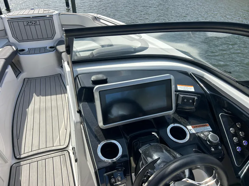 Slide: The Image of 2023 Yamaha Boats 252SD dashboard with touchscreen and steering wheel, docked on water. - 29