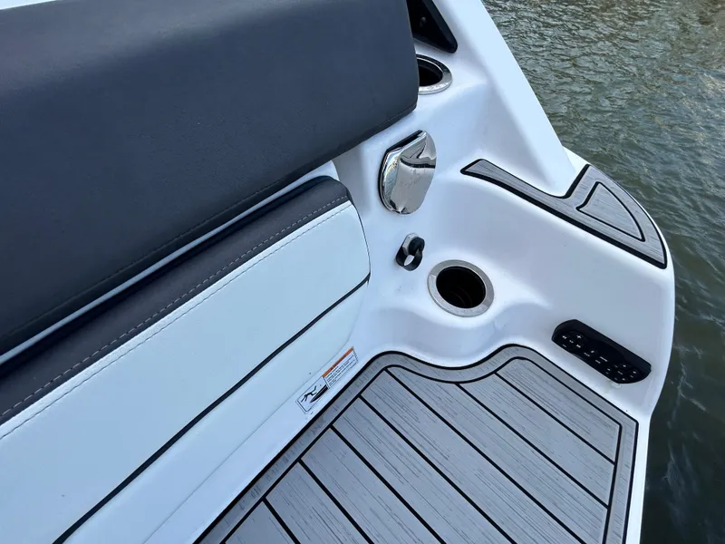 Slide: The Image of 2023 Yamaha Boats 252SD interior detail with seating and cup holder by the water. - 49