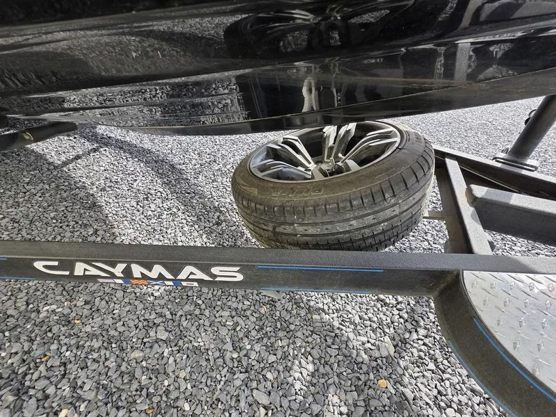 Slide: The Image of 2021 Caymas CX 21 boat trailer with spare tire on gravel surface. - 21
