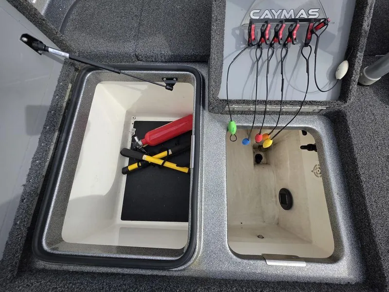 Slide: The Image of Storage compartments in a 2021 Caymas CX 21 boat with tools and wiring. - 29