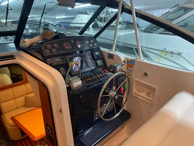 Slide: The Image of 2002 Tiara Yachts 3500 Open helm with steering wheel and control panel in a marina setting. - 11