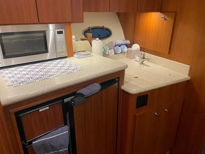 Slide: The Image of 2002 Tiara Yachts 3500 Open galley with microwave, sink, and wooden cabinetry. - 17