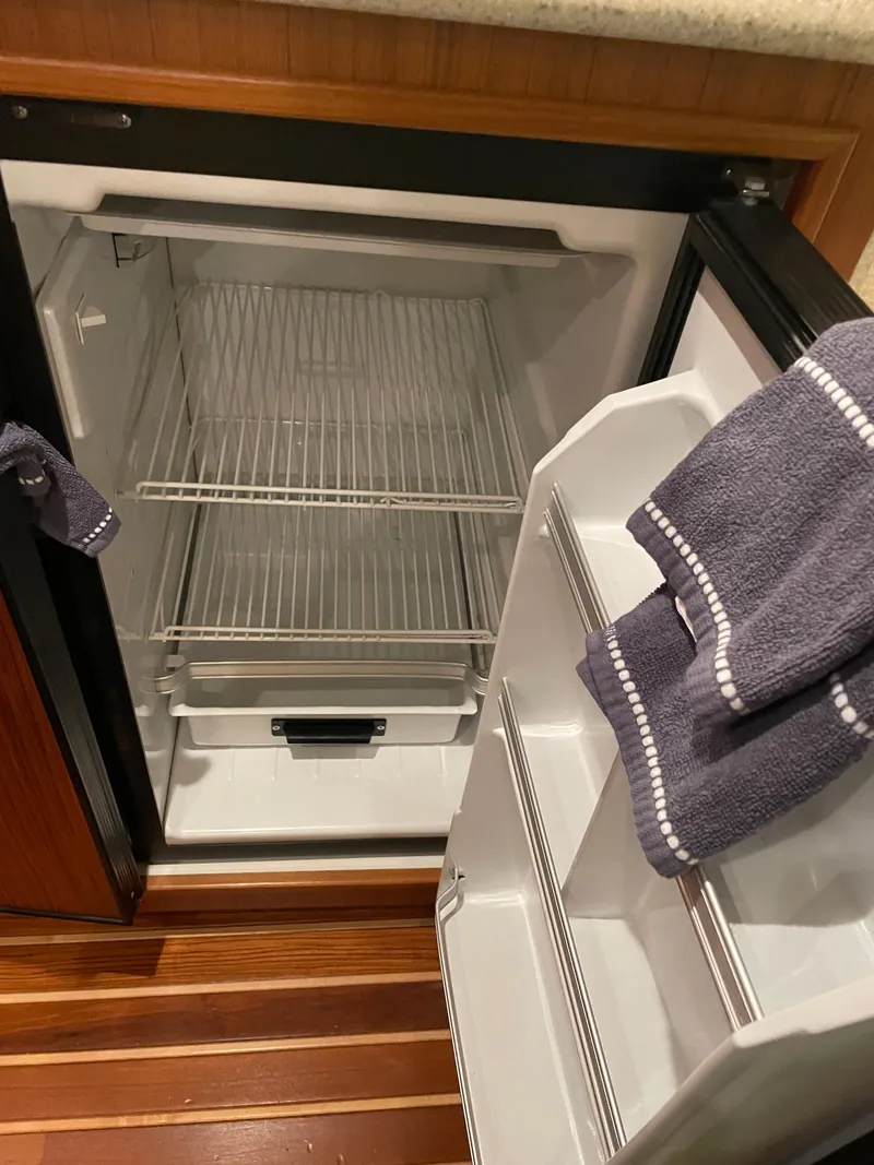 Slide: The Image of Open refrigerator inside a 2002 Tiara Yachts 3500 Open, with wooden flooring and towels. - 24