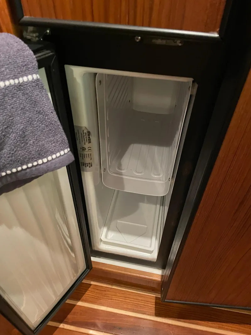 Slide: The Image of Open refrigerator inside 2002 Tiara Yachts 3500 Open, with wooden interior detailing. - 25