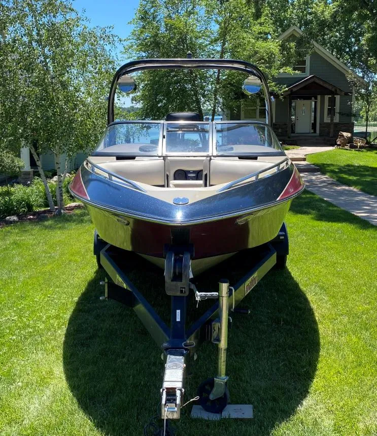 Slide: The Image of 2007 Malibu Wakesetter 23 LSV boat on trailer, parked on grass, with trees and house in background. - 2