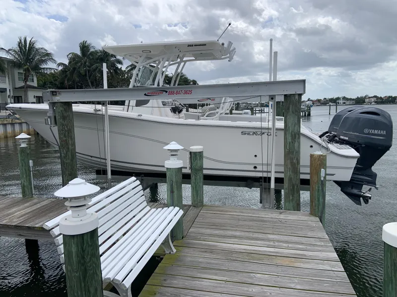 Slide: The Image of 2019 Sea Fox 266 Commander boat docked, featuring Yamaha engine, wooden pier, and tropical backdrop. - 0