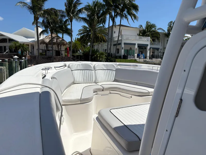 Slide: The Image of 2019 Sea Fox 266 Commander boat interior with cushioned seating, docked near palm trees and houses. - 19