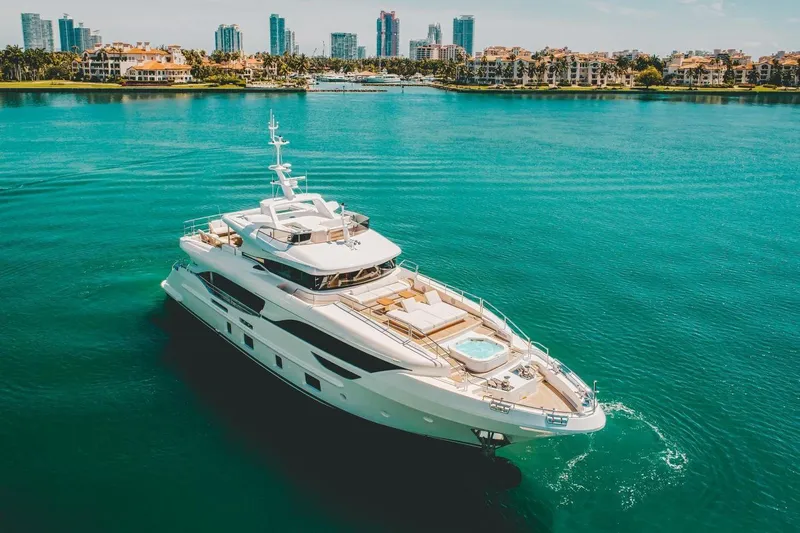 Slide: The Image of Luxurious 2020 Benetti Delfino yacht cruising in turquoise waters near a city skyline. - 4