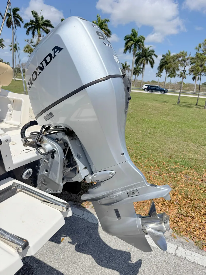 Slide: The Image of 2016 Key West 1720 Center Console with Honda outboard motor, parked near palm trees. - 26