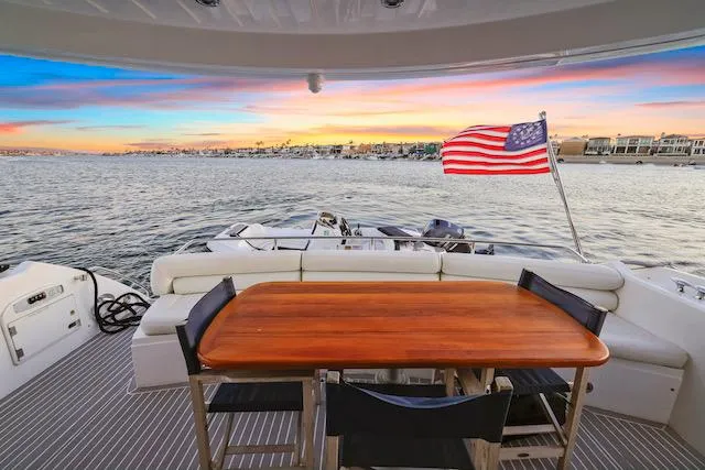 Slide: The Image of Sunseeker Manhattan 60 yacht deck with sunset view, American flag, and waterfront cityscape, 2008 model. - 11