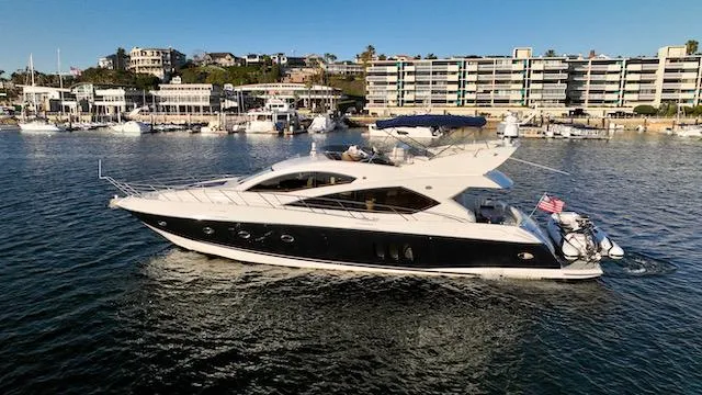Slide: The Image of 2008 Sunseeker Manhattan 60 yacht cruising near a marina with modern buildings. - 40