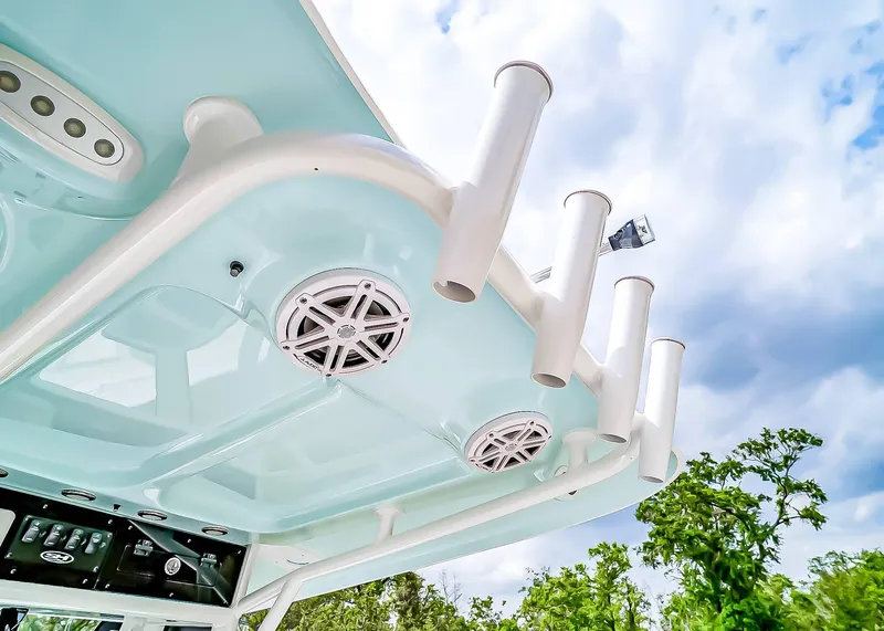 Slide: The Image of 2025 Sea Hunt Ultra 245 SE boat roof with rod holders and speakers against a cloudy sky. - 21