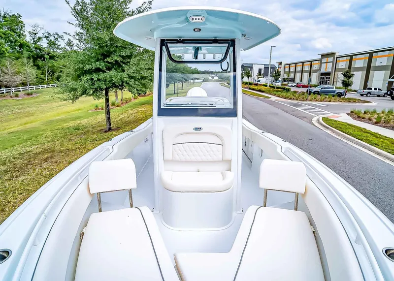 Slide: The Image of 2025 Sea Hunt Ultra 245 SE boat with sleek design, parked near greenery and modern buildings. - 22