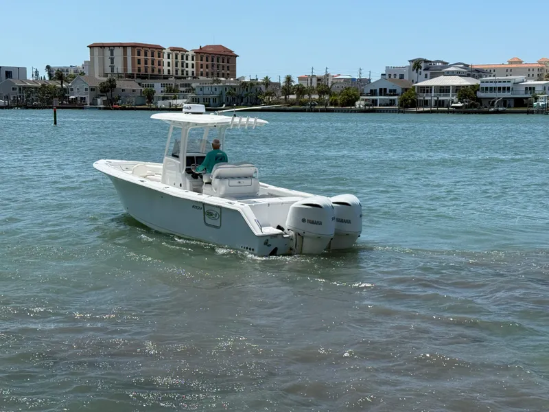 Slide: The Image of 2016 Sea Hunt Gamefish 27 boat cruising on a sunny day near waterfront buildings. - 30