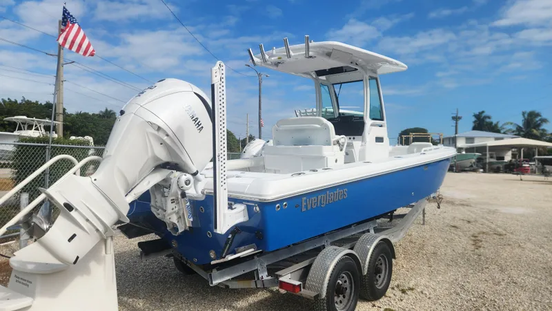 Slide: The Image of 2025 Everglades 253 Center Console boat on trailer, blue hull, outboard motor, American flag in background. - 3