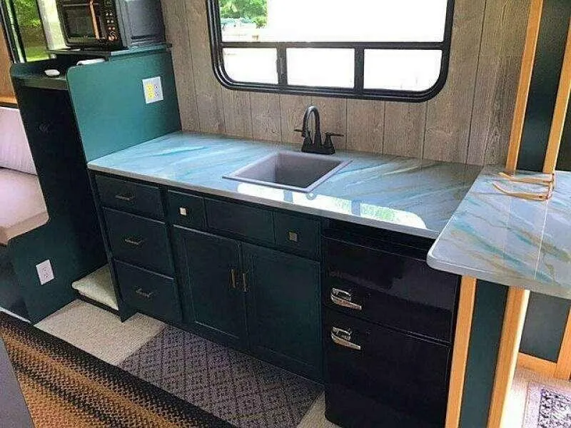 Slide: The Image of Modern RV kitchen with teal cabinets, marble countertop, and black sink, Custom 25 model, 2023. - 11