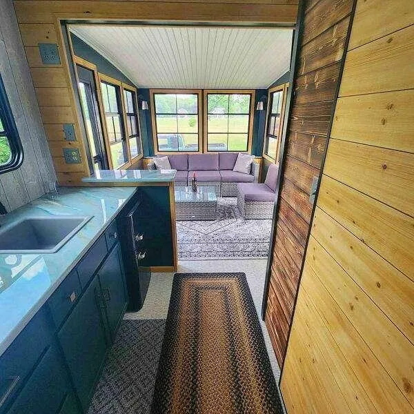 Slide: The Image of Modern tiny home interior with kitchen, cozy seating area, and large windows, 2023 model. - 12