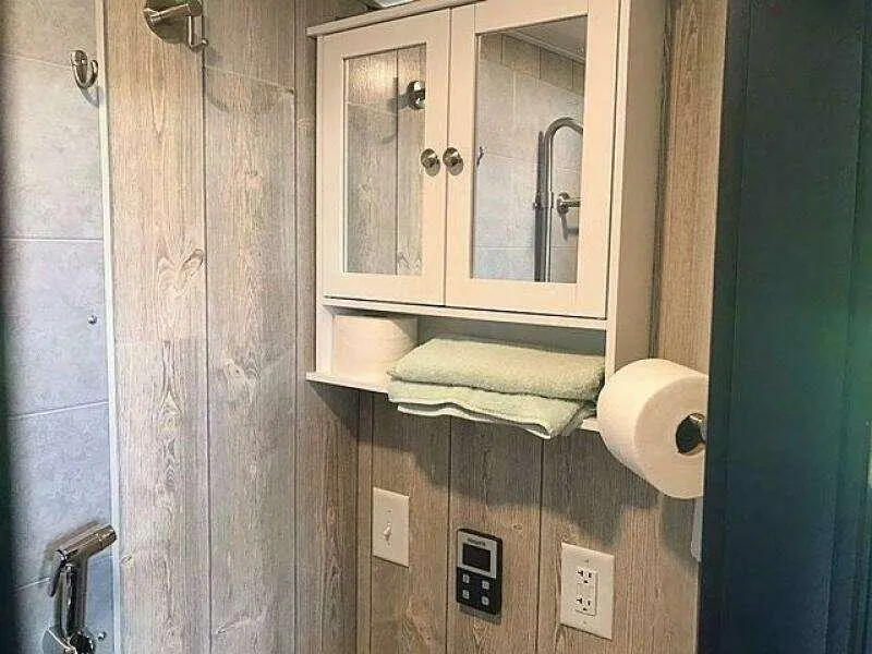 Slide: The Image of Compact bathroom with wooden walls, mirrored cabinet, towel, and toilet paper holder. - 13