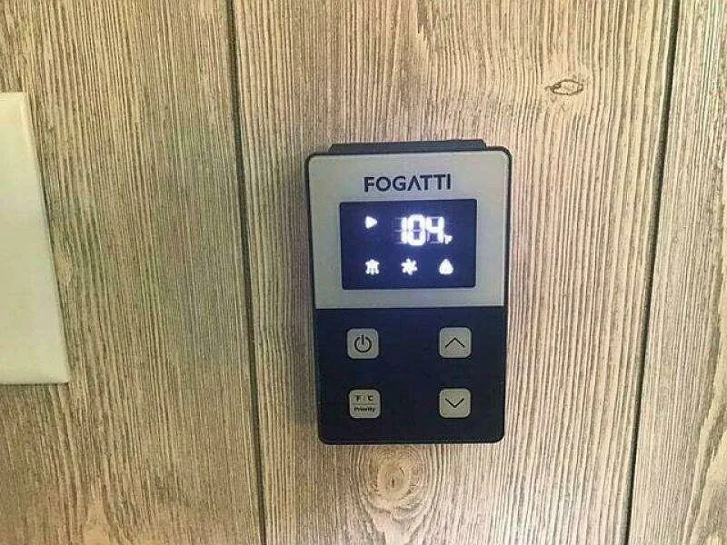 Slide: The Image of Digital thermostat on wooden wall displaying temperature, model Custom 25, year 2023. - 21