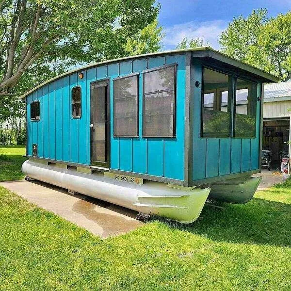 Slide: The Image of Blue custom houseboat on grass, 2023 model, with large windows and pontoon base. - 30