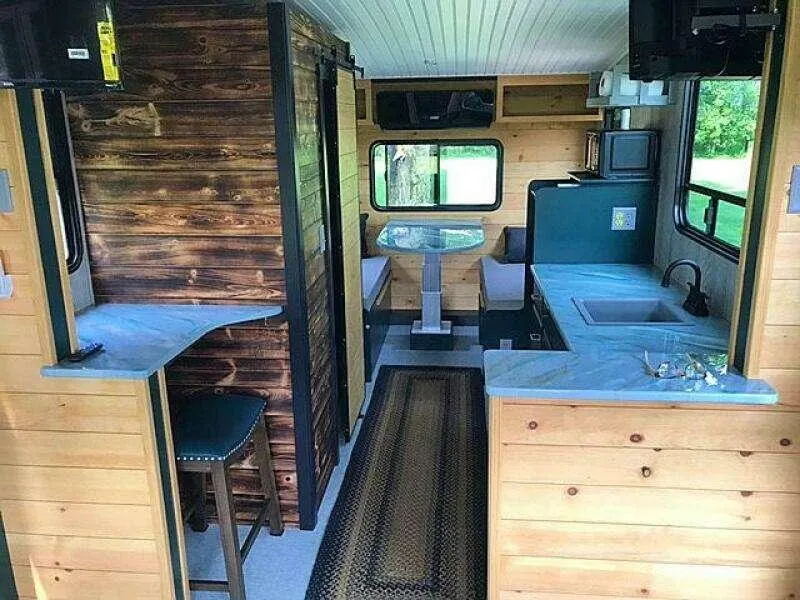Slide: The Image of Custom 2023 RV interior with wood paneling, kitchenette, and dining area. - 5