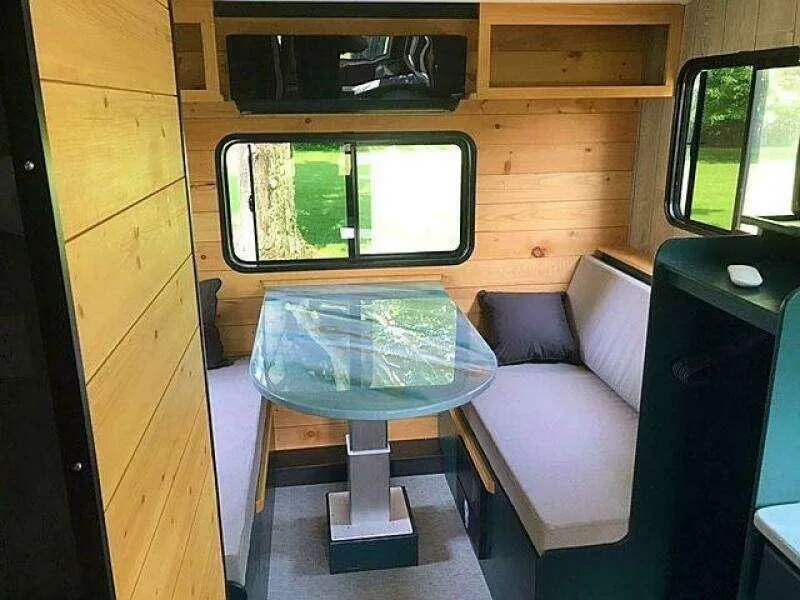 Slide: The Image of Cozy custom camper interior with wooden walls, glass table, and cushioned seating, 2023 model. - 6