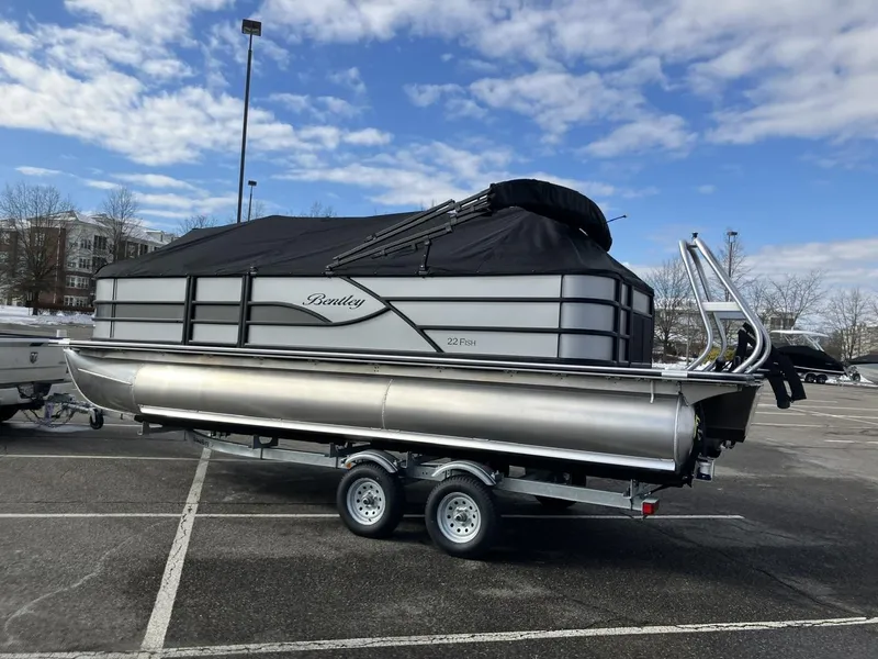 Slide: The Image of 2025 Bentley Pontoons 223 Fish-N-Cruise on trailer in parking lot, under cloudy sky. - 2