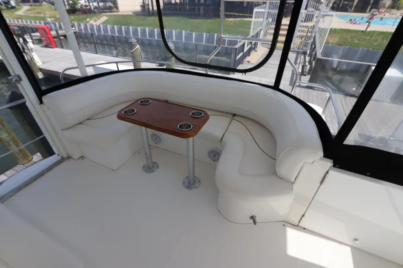 Slide: The Image of 2000 Cruisers Yachts 4450 Express Motoryacht interior with curved seating and wooden table. - 14