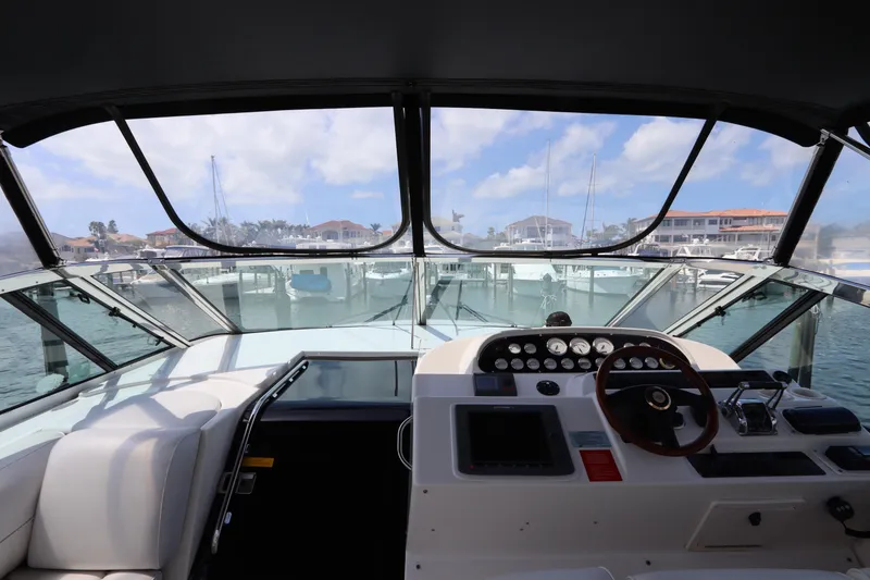 Slide: The Image of 2000 Cruisers Yachts 4450 Express Motoryacht helm view with marina backdrop. - 19