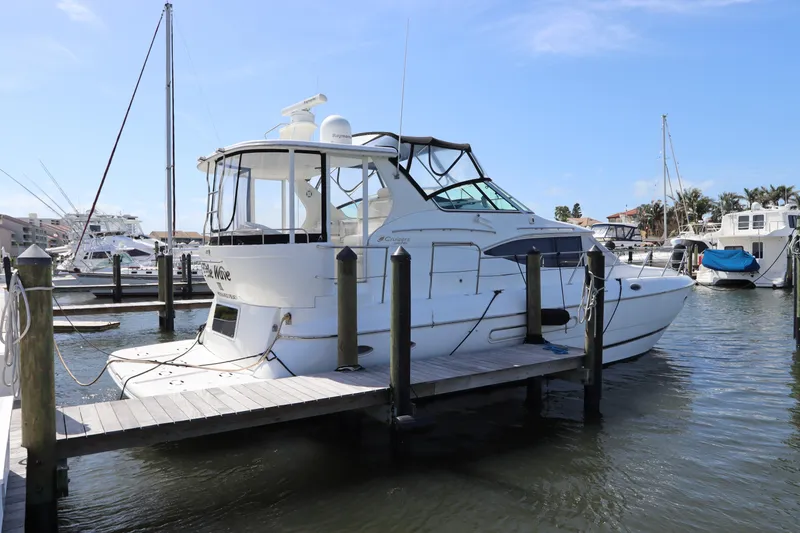 Slide: The Image of 2000 Cruisers Yachts 4450 Express Motoryacht docked at marina under clear blue sky. - 3