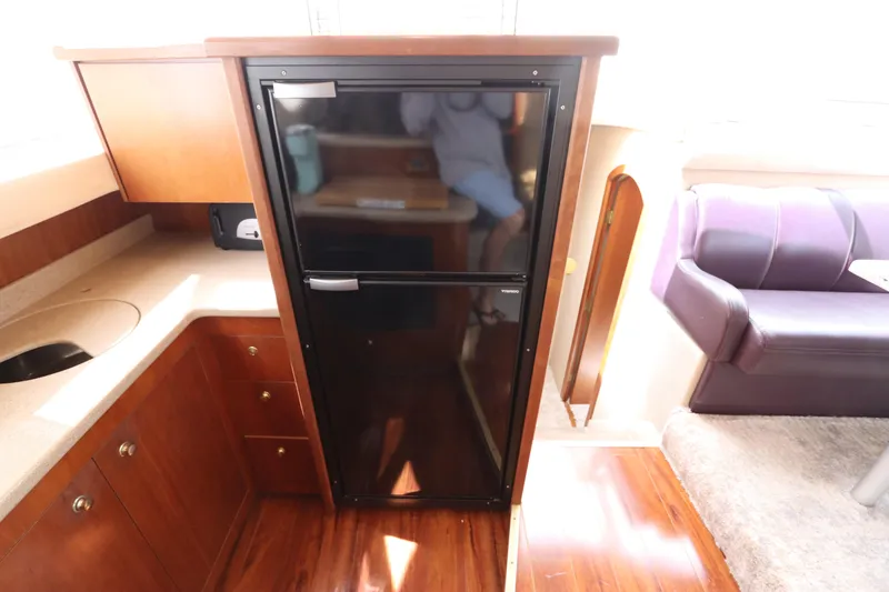Slide: The Image of Interior of 2000 Cruisers Yachts 4450 Express Motoryacht with fridge and wooden cabinetry. - 33