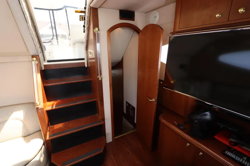 Slide: The Image of Interior of 2000 Cruisers Yachts 4450 Express Motoryacht with stairs, TV, and wooden cabinetry. - 43