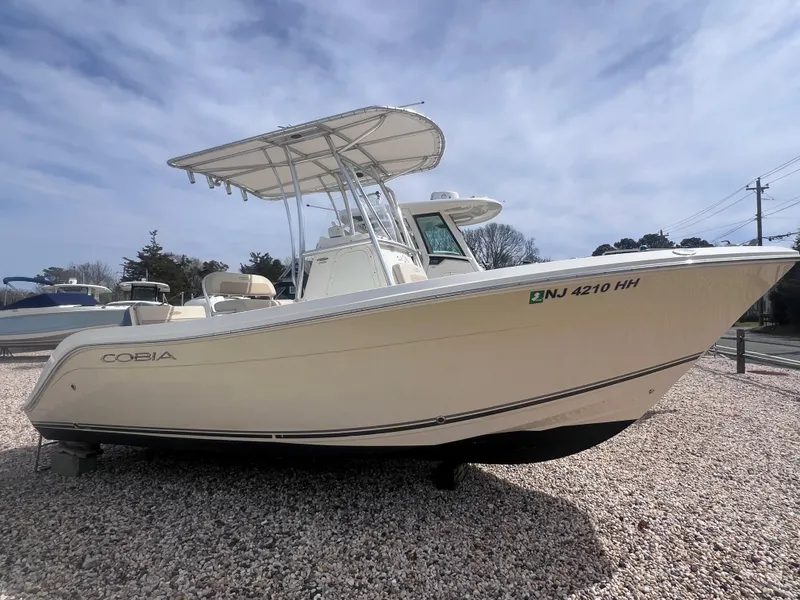Slide: The Image of 2014 Cobia 201 Center Console boat on gravel, side view, clear sky background. - 0