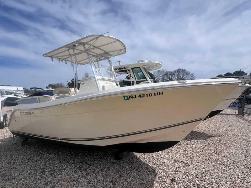 Slide: The Image of 2014 Cobia 201 Center Console boat on gravel, side view, under clear sky. - 1